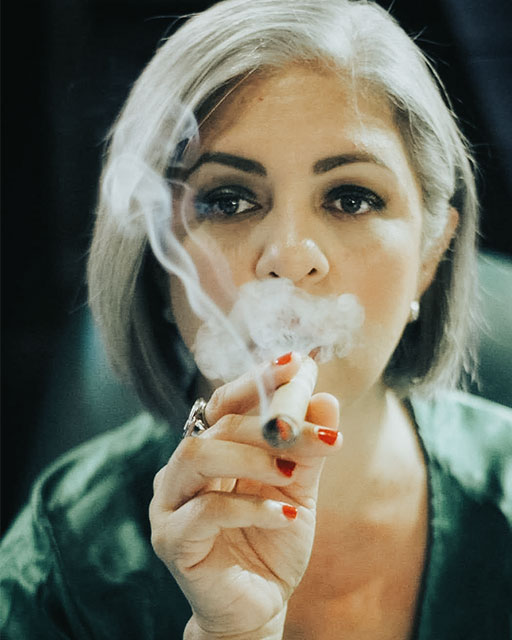 Cynthia Gonzalez (of Mujeres Entre Humos) in portrait, smoking a cigar